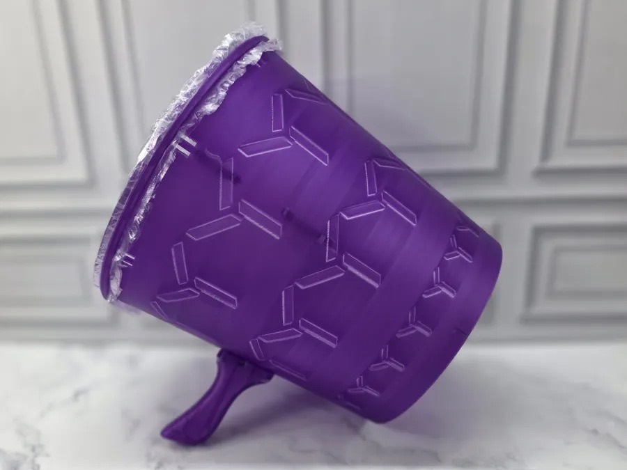 Cañón de vórtice morado impreso en 3D con su membrana de plástico, apoyado sobre una mesa de mármol